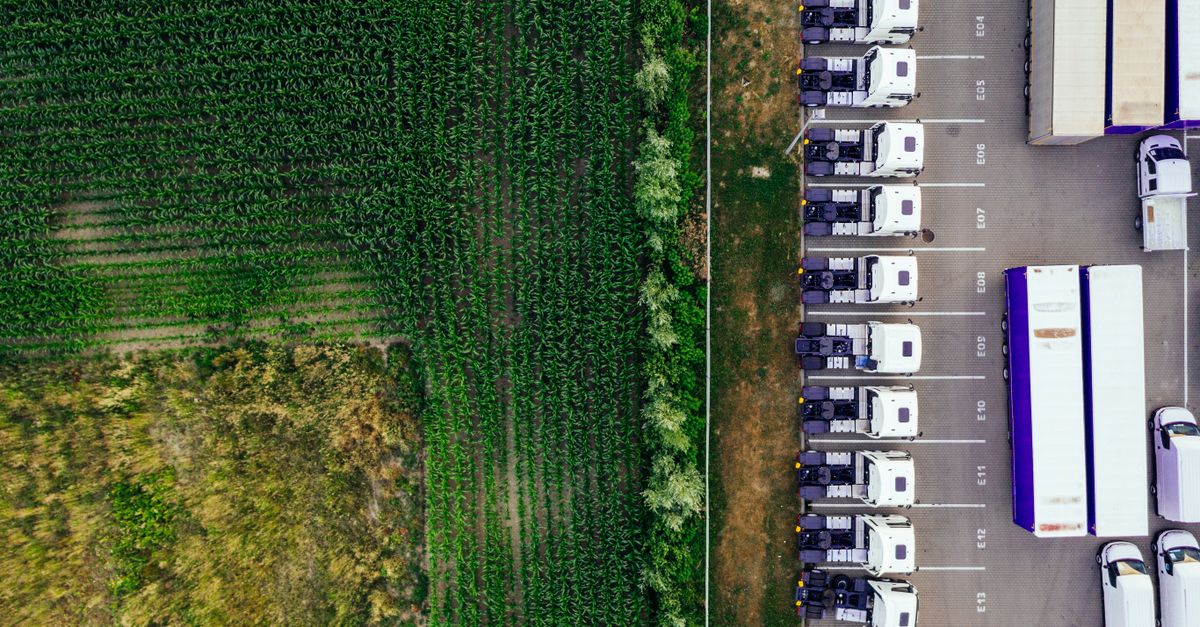 Drone shot of parked trucks next to a lush green cropland in Poznań, Poland.